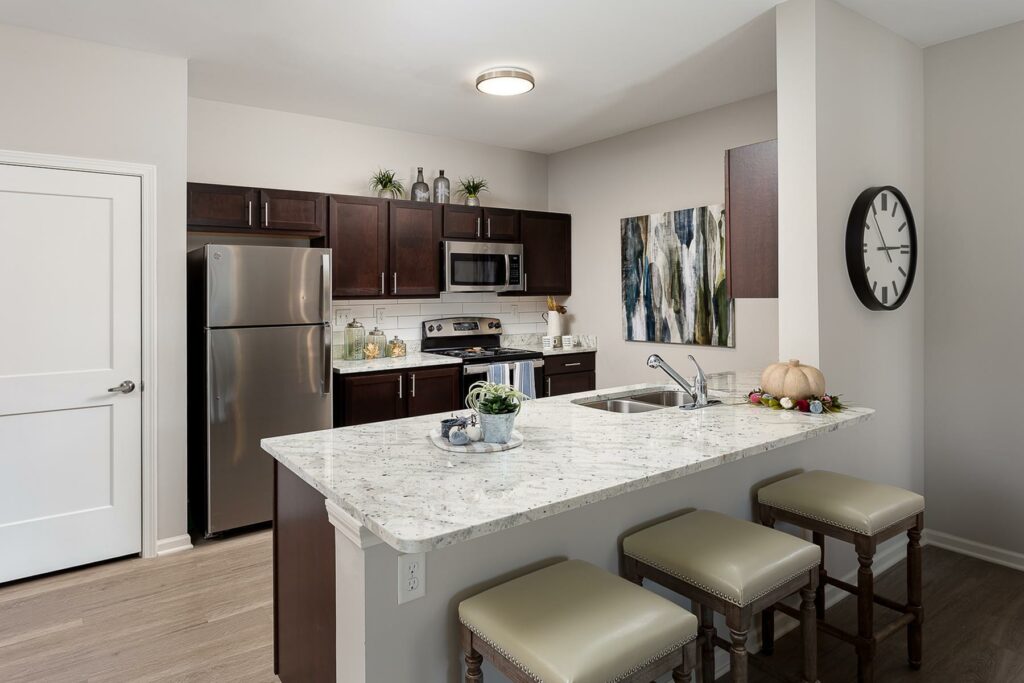 Gorgeous model kitchen with barstools, granite countertops, and stainless steel appliances